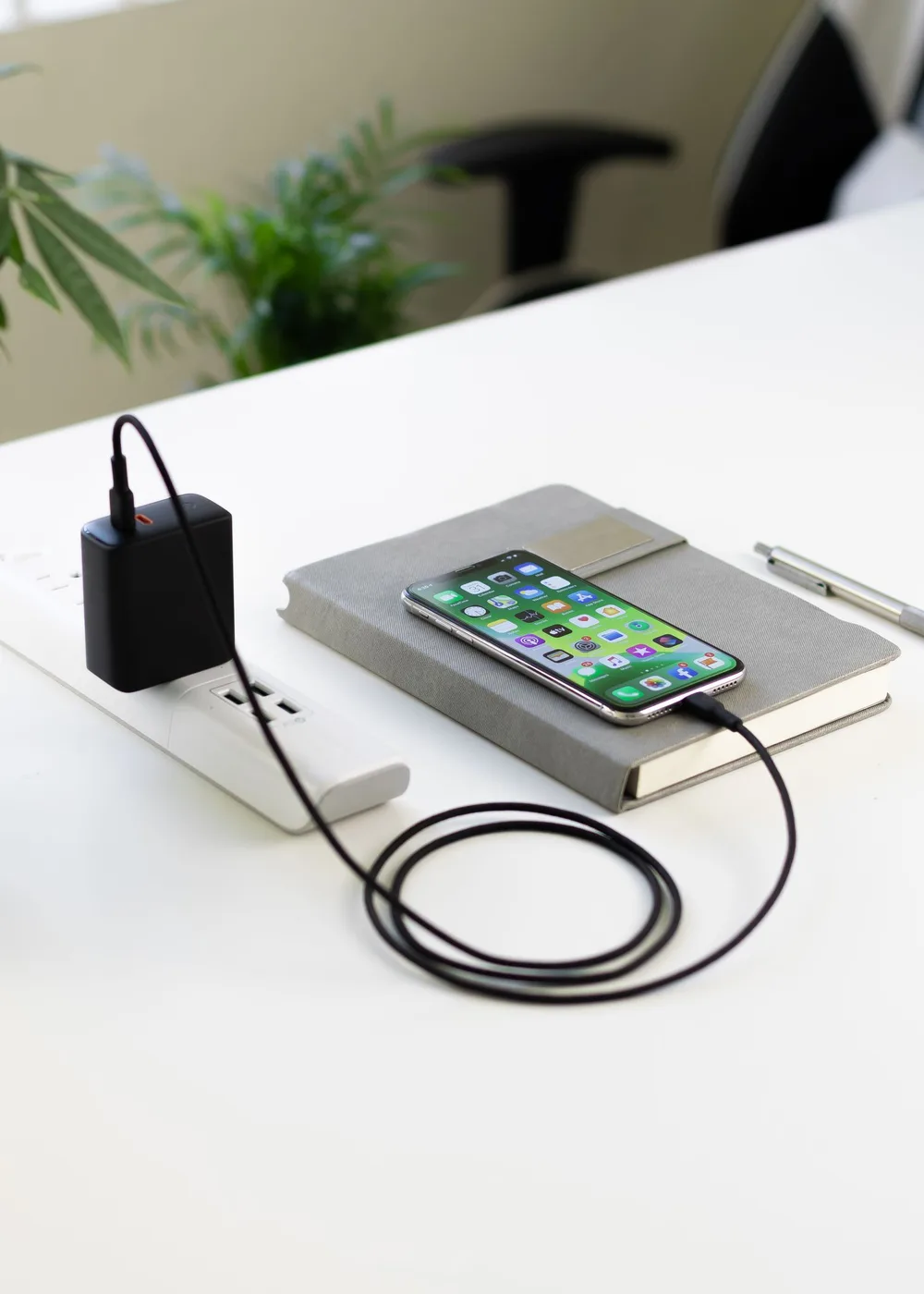 A phone charging on a notebook at a desk