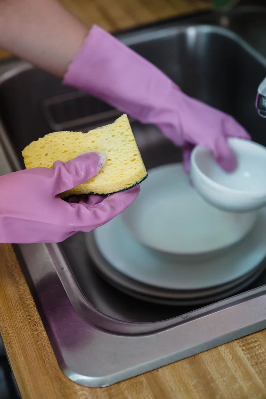 Dishes being washed by hand at a kitchen sink
